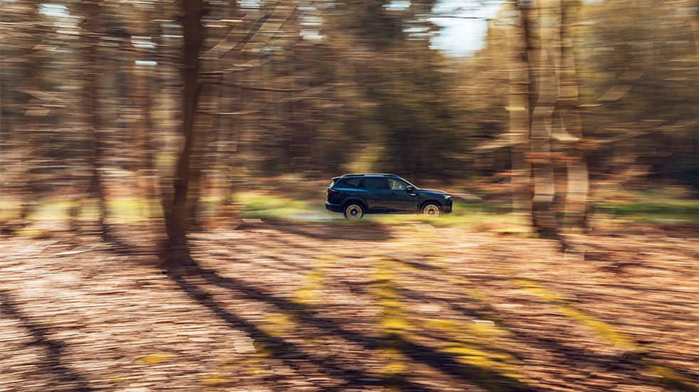 A shot of the Bigster SUV in focus and in motion, conveyed through the blurred woodland of Thetford Forest